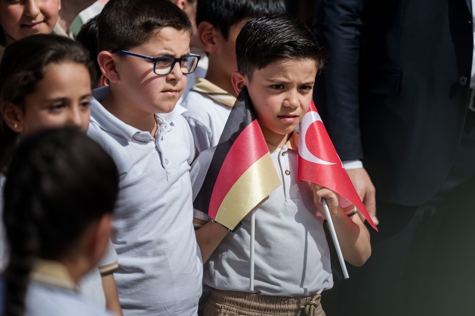 Zwei Schuljungen stehen nebeneinander, einer hat eine deutsche und eine türkische Flagge in der Hand